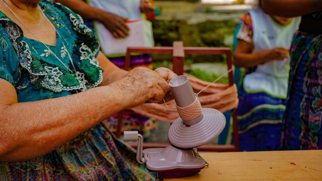 A woman skillfully operates a yarn spinner, showcasing traditional Guatemalan craftwork.